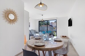 Zona de menjador amb taula rodona, cadires i lluminàries penjants.