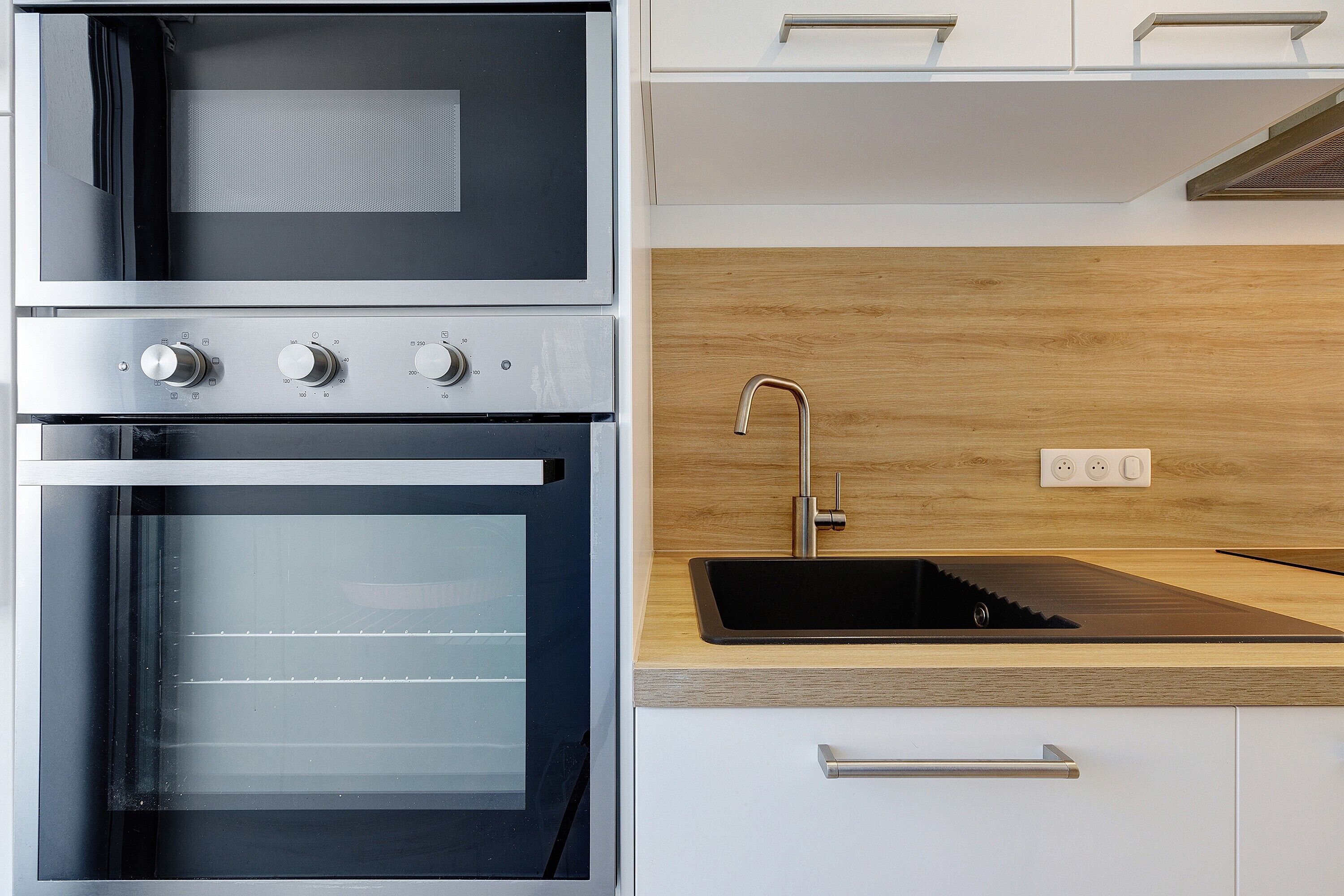 A kitchen with a built-in oven, a sink, and a wooden countertop.