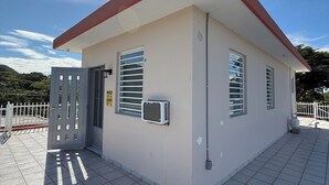 A small building with a red roof, a white door, and a window with blinds. - Sun bathed studio apartment with mountain views just minutes from the beach! (Rincón)