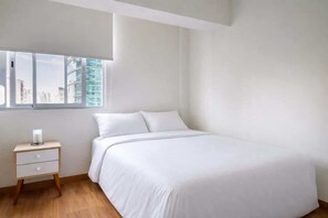 A minimalist bedroom with a large bed, a nightstand, and a window with a city view. - Centric and Cozy Apt 3bed 2.5 bath w/ Free parking (Miraflores)