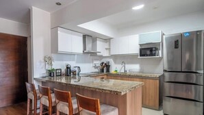 Eine moderne Küche mit einer zentralen Kochinsel, Edelstahlgeräten und Holzbarhocker.