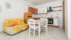 A compact kitchen with a dining table, a sofa, and a refrigerator. - Apartment 'I Ciottoli Dello Ionio - Apt 18' with Sea View, Shared Terrace and Balcony (Mascali)