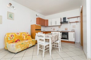Un angolo cottura compatto con un tavolo da pranzo, un divano e un frigorifero.
