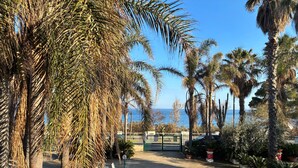 A paved pathway lined with palm trees and a view of the sea. - Apartment 'I Ciottoli Dello Ionio - Apt 18' with Sea View, Shared Terrace and Balcony (Mascali)