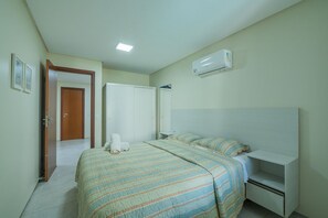 A bedroom with a bed, bedside table, and an air conditioning unit. - Scopa Beach #c3-200 - Beachfront By Carpediem (Aquiraz)