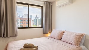 A hotel room with a large bed, a window with curtains, and a view of buildings outside. - Buenos Ayres #509 - Apt With Balcony by Carpediem (João Pessoa)