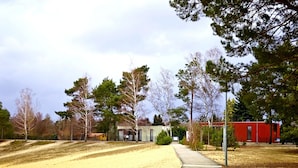 A rural landscape with a dirt path leading to a small building, surrounded by trees and open fields. - Bernsteinsee Homes and Ferien Beach House (Sassenburg)