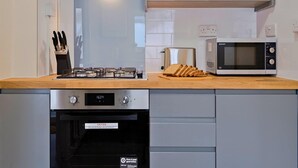 A modern kitchen with a gas stove, oven, microwave, and a toaster. - 2-bedroom Bright London Home (London)