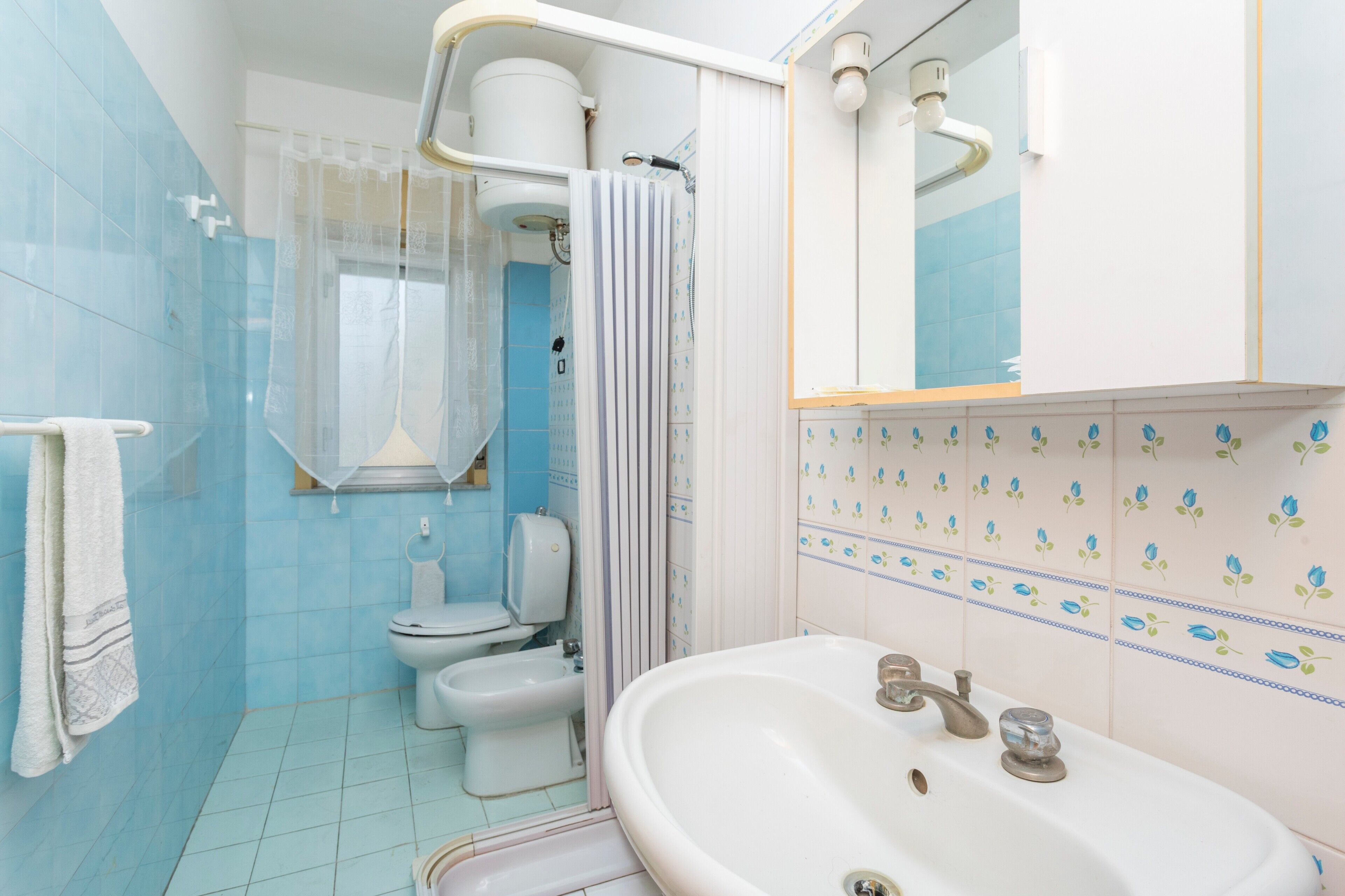 Un bany amb vàter, bidet, rentapel obert i cortina de dutxa.