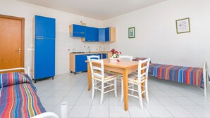 Une pièce compacte comprenant un coin cuisine, une table à manger avec des chaises, un lit et une petite table de chevet.