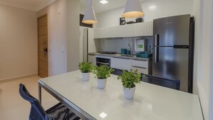 Una cucina moderna con frigorifero in acciaio inossidabile, mobili bianchi e illuminazione a sospensione.
