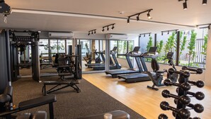 Ett gym med löpband, styrketräningsmaskiner och en vägg full av speglar.