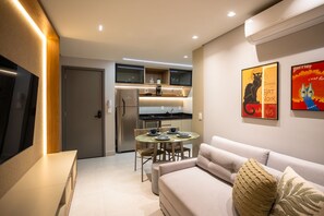 A modern living room with a sofa, a coffee table, and a dining area with a table and chairs. - Jardins Almare Number 431 - Seafront by Carpediem (João Pessoa)