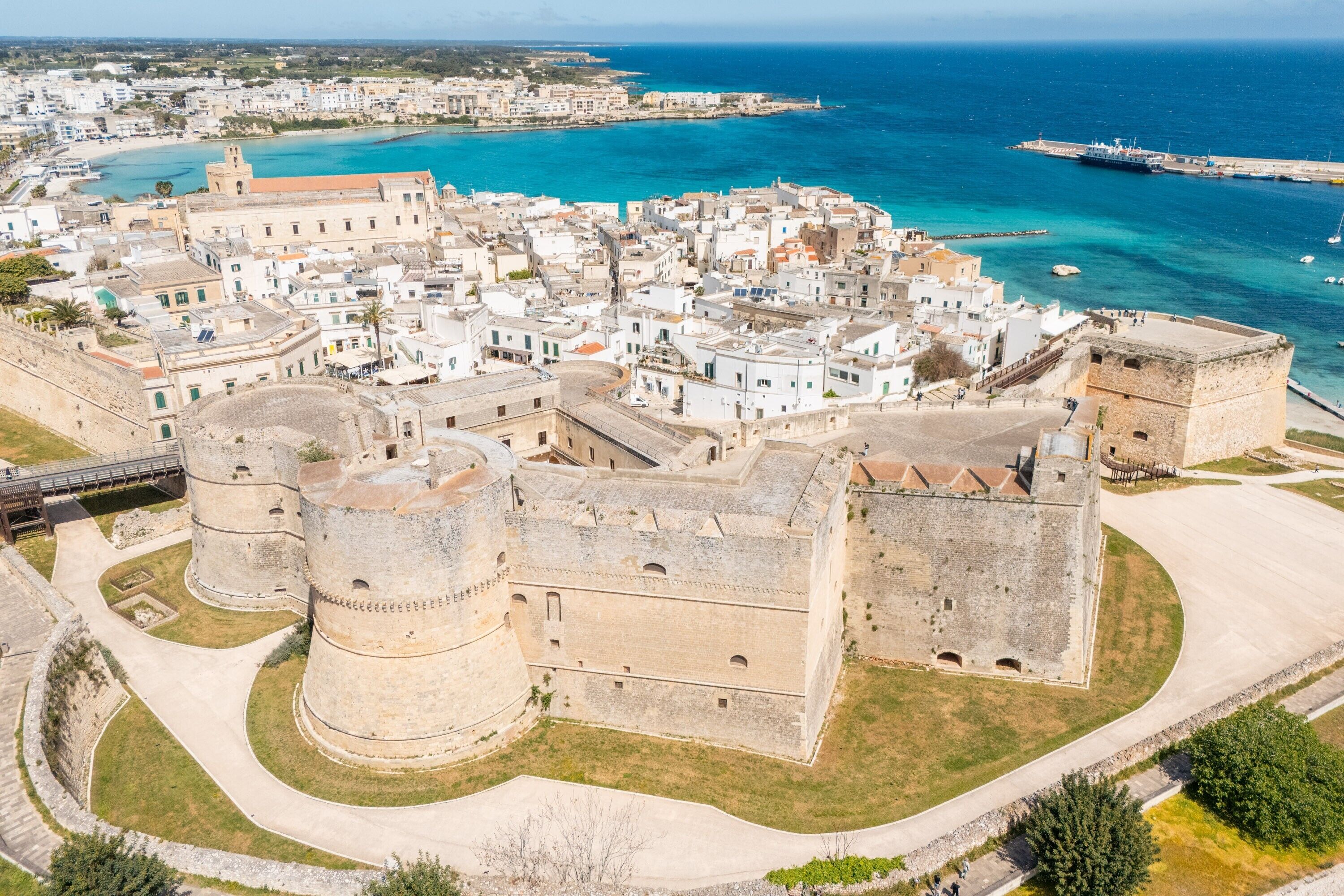A coastal town with historic stone buildings, a prominent fort, and a clear view of the sea.