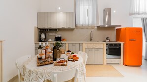 Eine moderne Küche mit Esstisch, gedecktem für eine Mahlzeit, einem leuchtend orangefarbenen Kühlschrank und einem eingebauten Backofen.