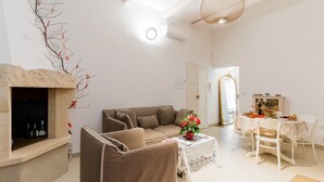 Ein Wohnzimmer mit einer Couch, einem Esstisch mit Stühlen, einem Kamin und einem Spiegel.