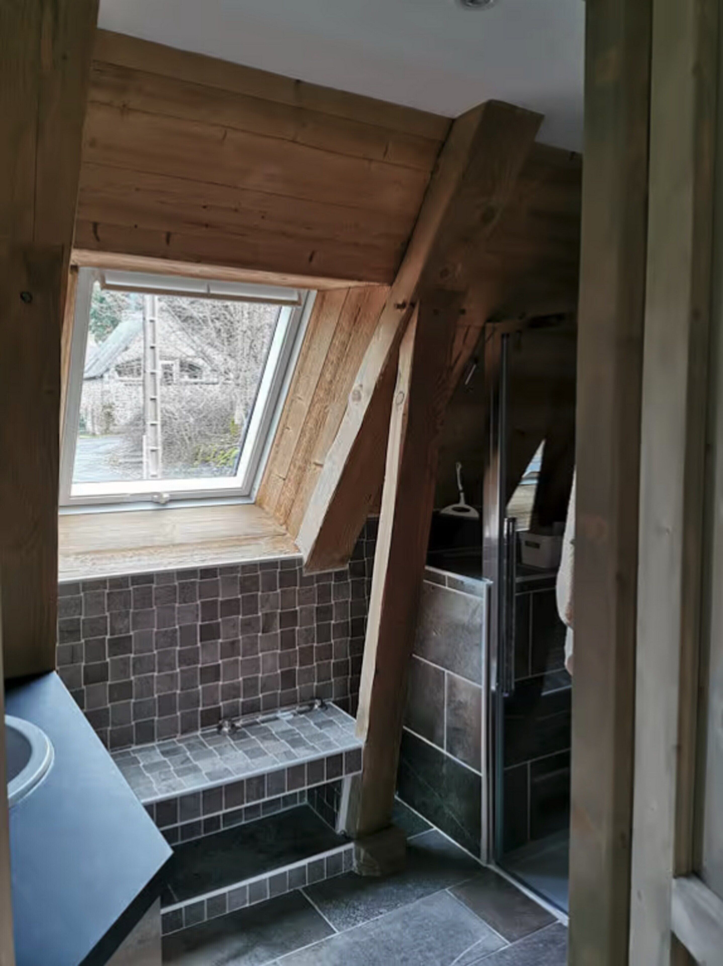 A bathroom with a skylight, tiled walls, and a shower area.