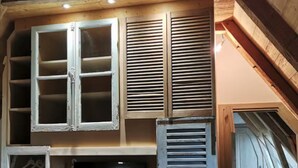 A compact attic room with a television, wooden cabinets, and a small wardrobe. - Rustic Mont-dore Family Cottage (Mont-Dore)