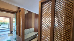 A modern interior with a sofa, wooden partitions, and a glass door leading outside. - Everglow Retreat White Tulip Guest House (Srinagar)