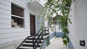 A staircase leading to a door, a checkered floor, and a wall with a cross symbol. - Everglow Retreat White Tulip Guest House (Srinagar)