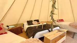A cozy tent with two beds, a wooden table, and a hanging plant. - Dovedale (Ashbourne)