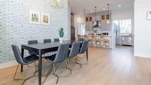 Een moderne keuken met witte kastjes, een centraal eiland en hanglampen.