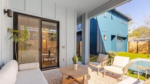 Een moderne buitenruimte met een bank, stoelen, een tafel en een zwembad.