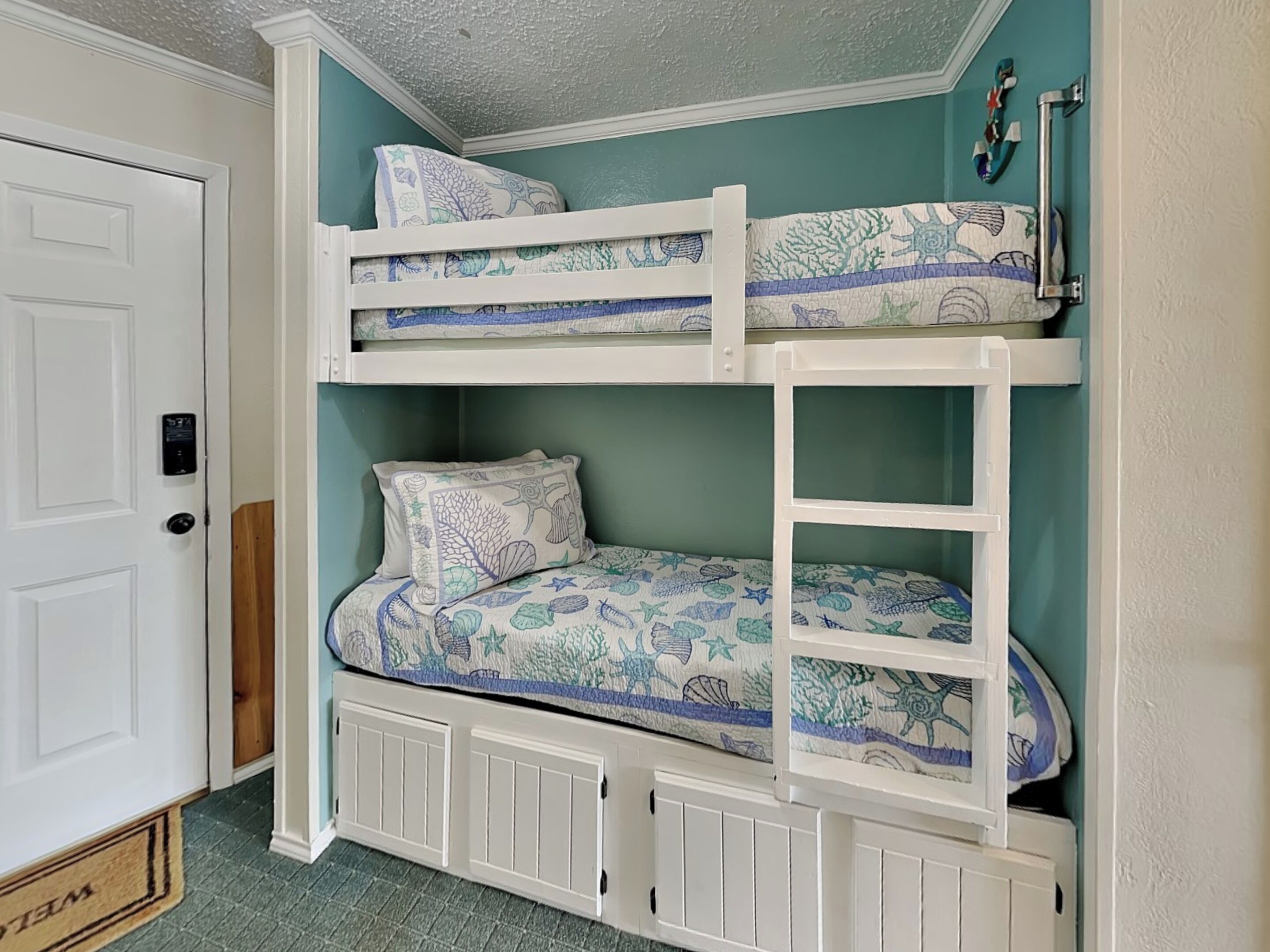 A bunk bed with a lower bunk and a door to the left.