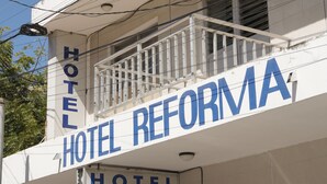 Een hotel genaamd "Hotel Reforma" met een balkon, een bord waarop "Familiar" kamers staan aangegeven en het getal "64" op het gebouw.