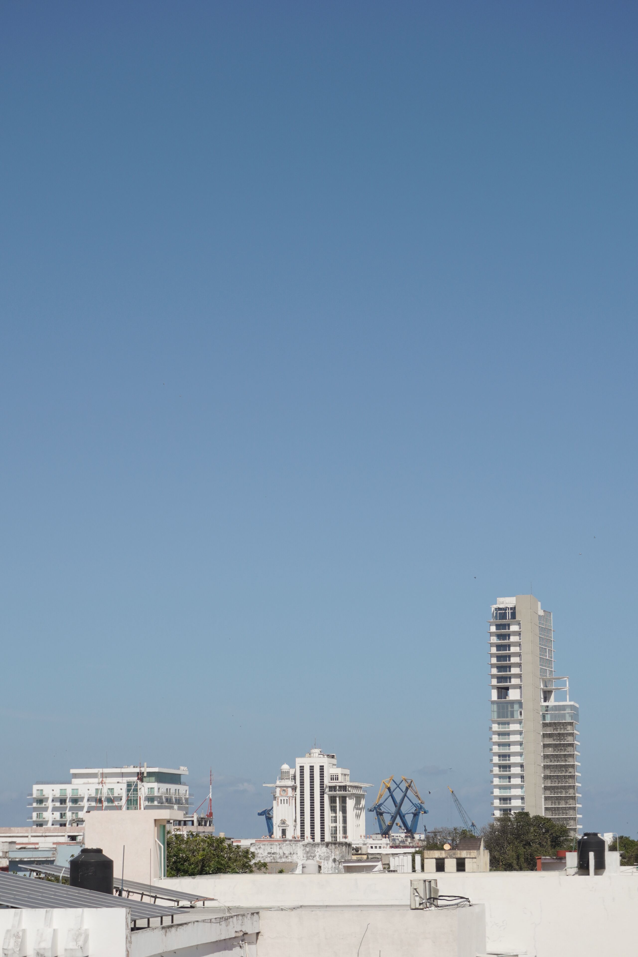 Un paisaje urbano con edificios modernos, incluyendo un rascacielos y un edificio con una estructura geométrica singular.