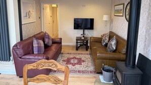 A living room with two sofas, a television, a fireplace, and a coffee sign. - Blakelaw Court (Alnwick)