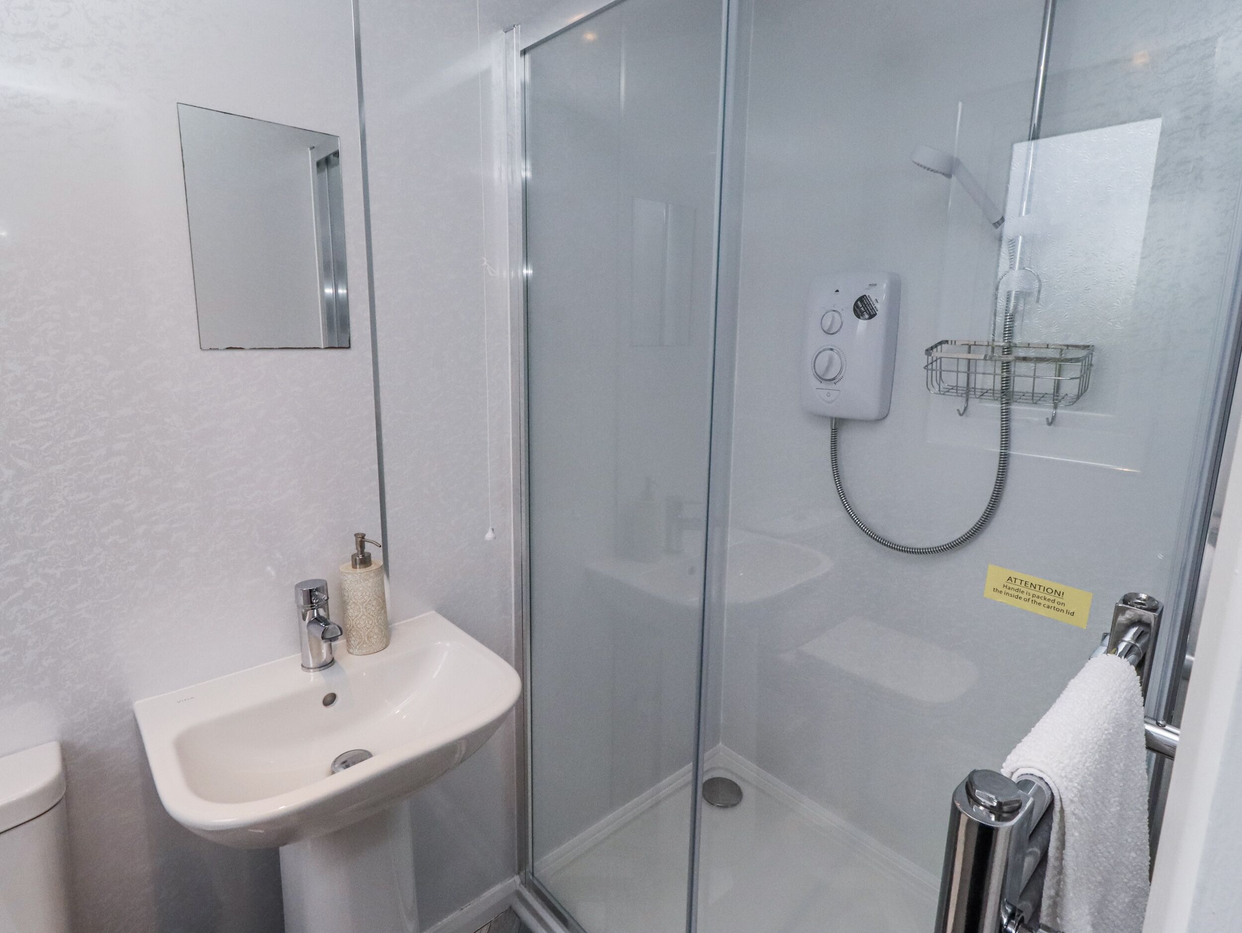 A modern bathroom with a glass shower enclosure, a sink, and a toilet.