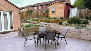 A patio with a table and chairs, surrounded by a garden with various plants and flowers. - Blakelaw Court (Alnwick)