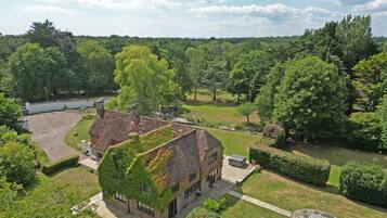 A house with a brick exterior and ivy-covered roof, surrounded by a well-maintained garden and a small pond.