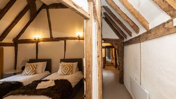 A bedroom with two beds, wooden beams, and a sloped ceiling.