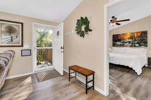 A bedroom with a bed, a bench, a ceiling fan, and a view of a forest through the window. - Yosemite Nature Escape: Pvt Gem • Pets • BBQ • Cozy • Split BRs (Mariposa)