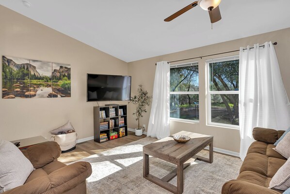 A living room with a flat-screen TV, a bookshelf, a coffee table, and a sofa.