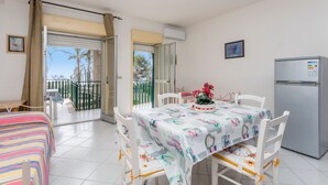 A room with a bed, a dining table with chairs, a refrigerator, and a balcony with a view. - Apartment 'I Ciottoli Dello Ionio - Apt 10' with Sea View, Shared Terrace and Balcony (Mascali)