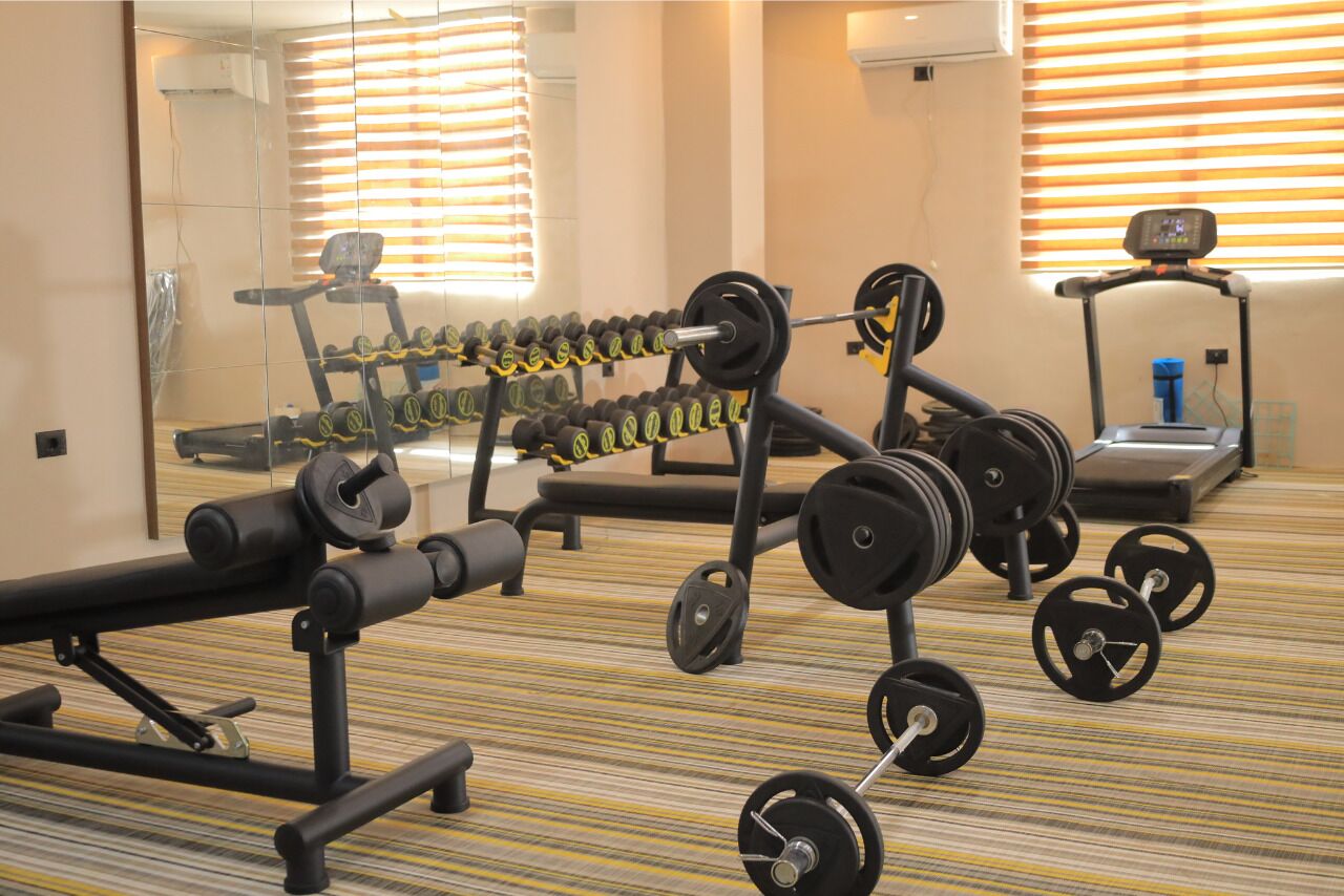 A gym with various exercise equipment including dumbbells, a bench, and a treadmill.