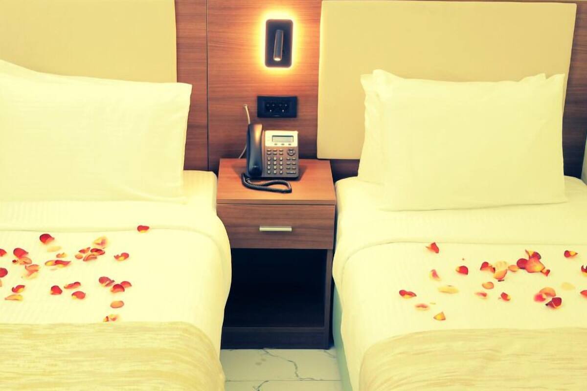 A hotel room with two beds, a bedside telephone, and a nightstand.