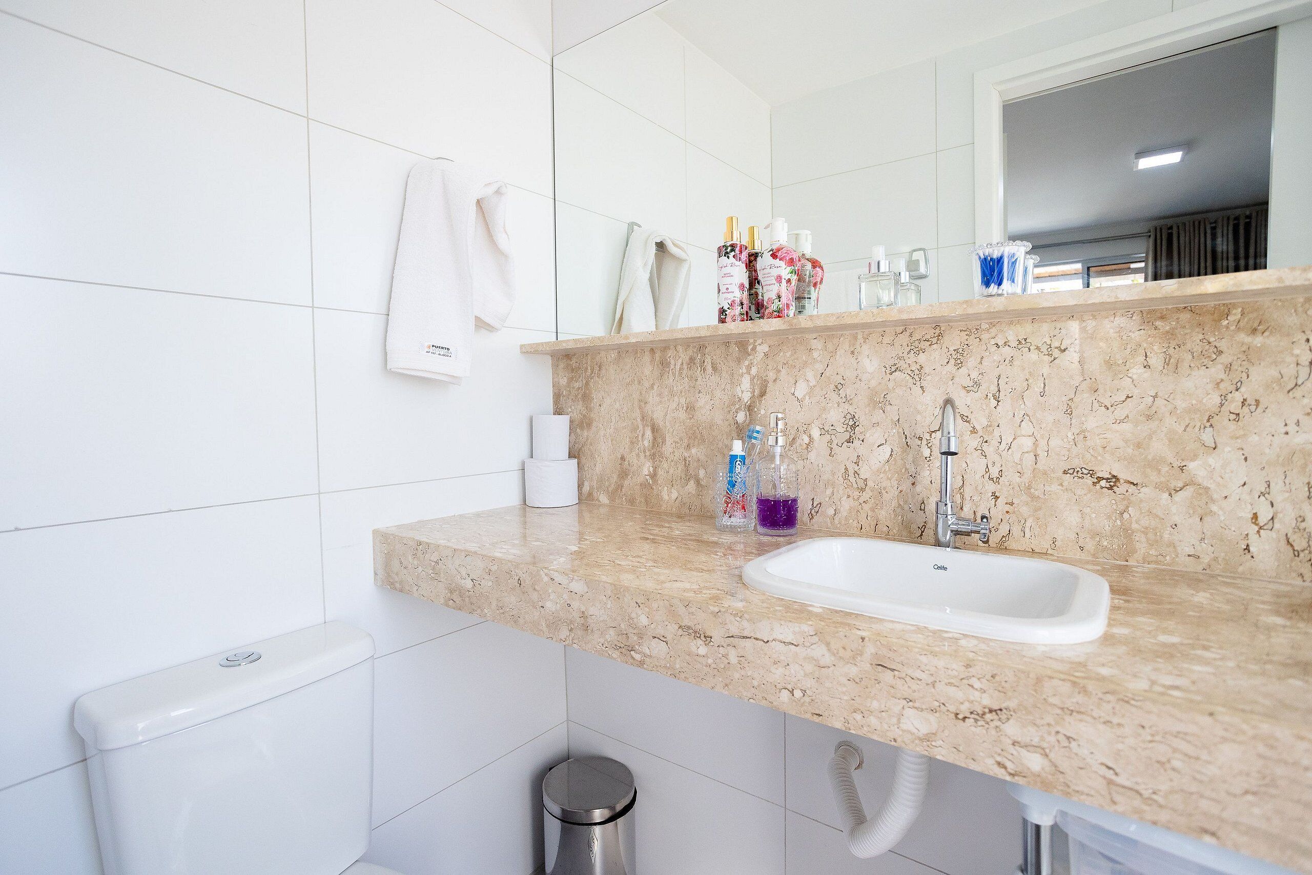 A bathroom with a marble countertop, a white sink, and a toilet.