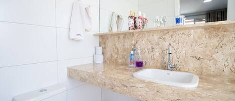 A bathroom with a marble countertop, a white sink, and a toilet.