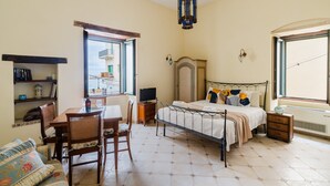 Een slaapkamer met een bed, nachtkastje, stoel en een raam.