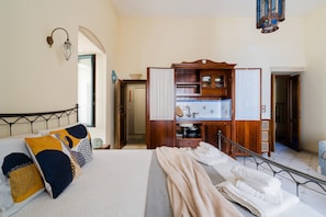 A hotel room with a bed, a wooden wardrobe, a bathroom with a sink and mirror, and a staircase leading to another room. - Holiday Home 'Mono Scilla Centro Storico Otranto' with Sea View, Wi-Fi & Air Conditioning (Otranto)