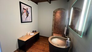 Ein Badezimmer mit Holzwaschtisch, großem Spiegel und gefliestem Duschbereich.