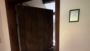 Eine Holztür, die zu einem Flur führt, an dessen Wand ein gerahmtes Bild hängt.