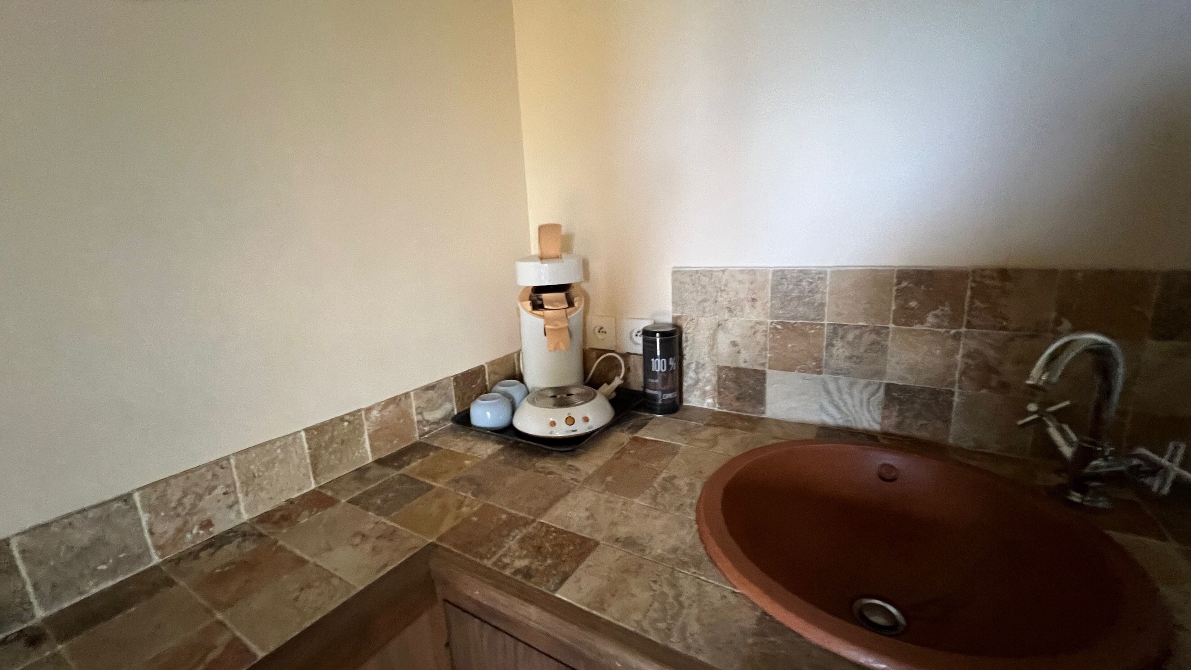 Ein Badezimmer mit Waschbecken, Spender für Handtücher und einer Kaffeemaschine.