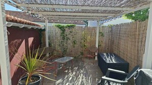 A covered patio with a table, chairs, a sofa, and a potted plant. - Beach Apartment 100m from the Sea (La Tranche-sur-Mer)