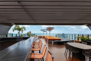 A deck with outdoor seating, a table, and umbrellas. - Setai Edition #113 - Seaside by Carpediem (João Pessoa)