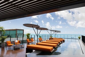 A rooftop lounge with orange seating, a glass balustrade, and a view of the sea. - Setai Edition #113 - Seaside by Carpediem (João Pessoa)